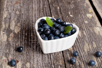 Heart shaped bowl of blueberries on wooden table
