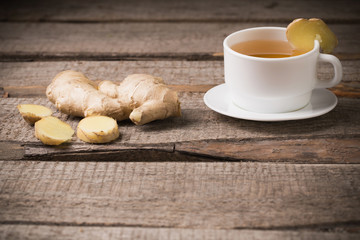 Ginger tea in a white cup on wooden background