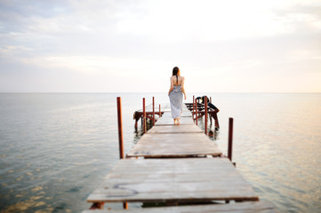 girl in a striped dress walking on a wooden bridge in the backgr