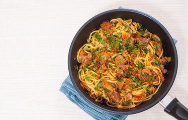 Pieces of meat and vegetables with spaghetti in a frying pan