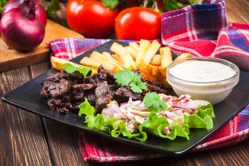 Kebab of beef with french fries and salad
