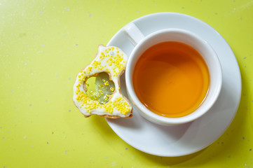 Ginger cookie and cup of tea on green background