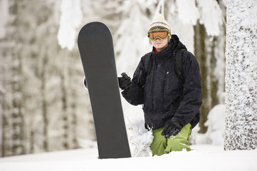 Snowboarder hold snowboard in forest
