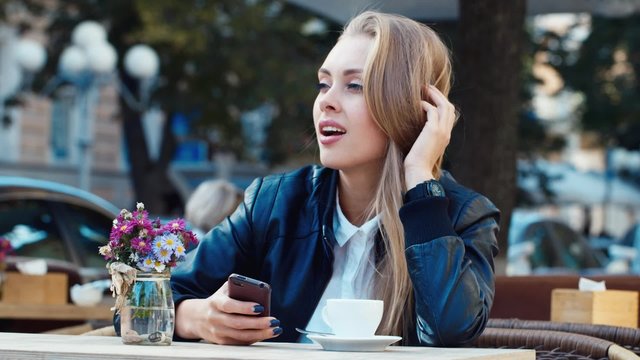 Attractive girl sitting in a cafe writing sms