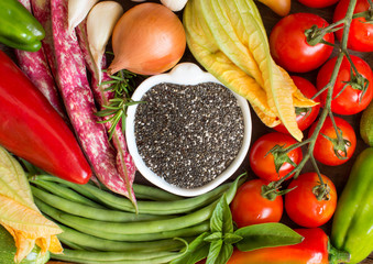 Raw chia seeds in bowl and vegetables