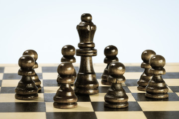 Team symbol with wooden chess pawns and chess queen.