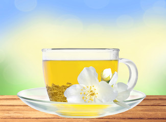 glass cup of green tea with jasmine flowers on wooden table