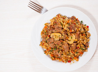 Rice with meat, vegetables and mushrooms on plate