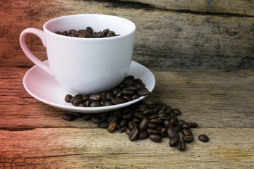 Cup full of coffee beans on wood