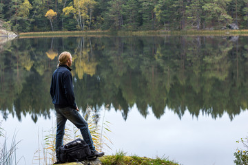 Fototapeta na wymiar Male hiker stoped to enjoy the view over an lake during an early fall morning hike