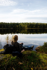 hiker taking a rest and have a cup of coffe by a lake