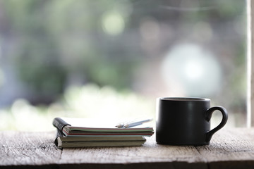 Notebook and black cup on wooden table