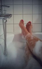 Mann mit lackierten Nägel in Badewanne