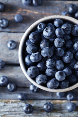 Blueberries in mug on a blue wooden background
