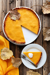 Tasty pumpkin pie on plate on a brown wooden table