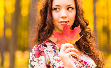 Young woman with autumn leaves in hand 