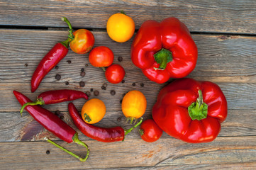 Chili pepper, paprika, red and yellow tomatoes on a wooden table