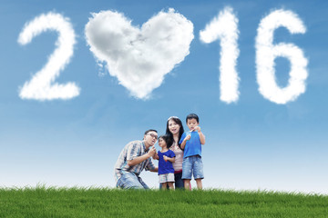 Family playing bubble at field with numbers 2016