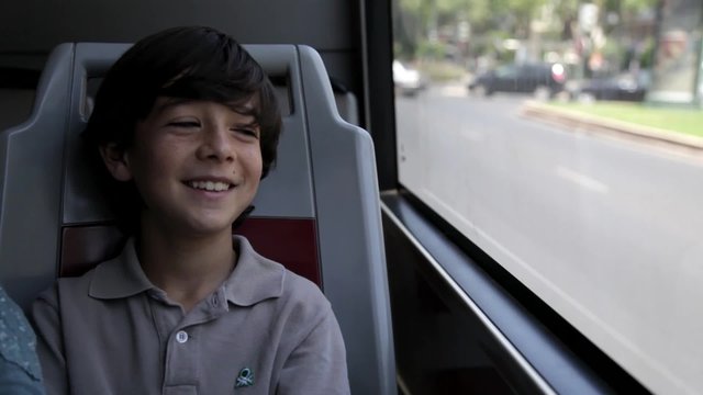 Niño mirando por la ventana del autobús mientras sonríe