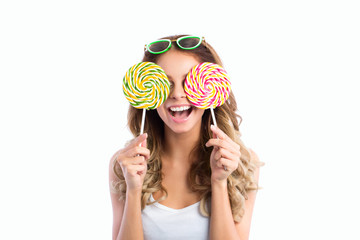 Woman in sunglasses smiling and holding two big lollipops.