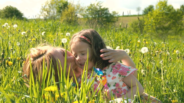 Mutter und Tochter kuscheln und spielen zusammen in einer Fr&uuml;hlingswiese - Teil 1