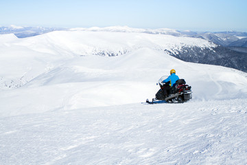 Fototapeta na wymiar Man on snowmobile in winter mountain.