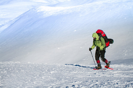 Winter hiking in the mountains on snowshoes with a backpack and tent.