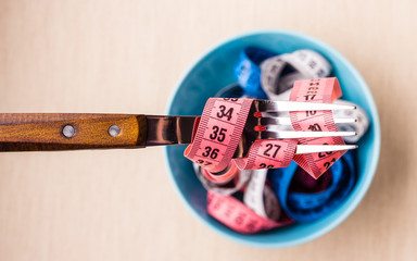Many colorful measuring tapes in bowl on table