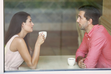Young couple drinking tea and talking in cafe