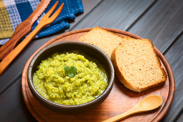 Homemade zucchini and parsley spread garnished with parsley, wholegrain bread on the side, photographed with natural light (Selective Focus, Focus on the leaf)