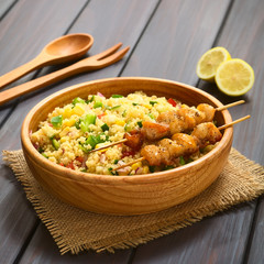 Couscous salad with bell pepper, tomato, cucumber, red onion, sweet corn, served with baked chicken on skewer. Photographed with natural light (Selective Focus, Focus one third into dish)