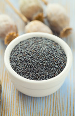 poppy seeds in a bowl on wooden surface