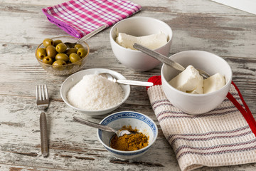 Formaggi cremosi, olive verdi denocciolate e curry in piccoli contenitori su un tavolo