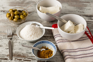 Formaggi cremosi, olive verdi denocciolate e curry in piccoli contenitori su un tavolo