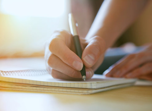 female hands with pen writing on notebook