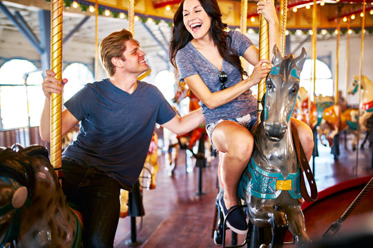 romantic couple on date having fun riding moving merry go round