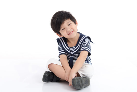Happy asian boy sitting on white background