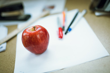 Apple on a white paper with pens. Back to school concept