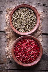 Red and green pepper  in bowls on wooden background