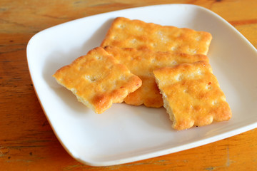 3 crackers on a square white plate on a table