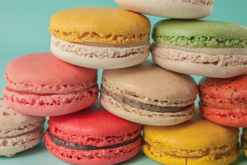 Pile of colorful macaroons stacked up like a tower in turquose pastel isolated background (Selective focus) - Closeup