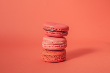 Pile of red-toned macaroons stacked up like a tower in red pastel isolated background