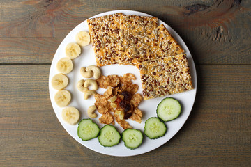 cookies, bananas, nuts and cucumbers on wooden background
