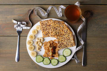 cookies, bananas, nuts and cucumbers, a measuring tape and Apple juice with utensils on wooden background