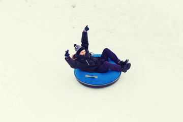 Fototapeta na wymiar happy young man sliding down on snow tube