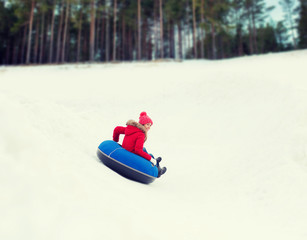 happy teenage girl sliding down on snow tube