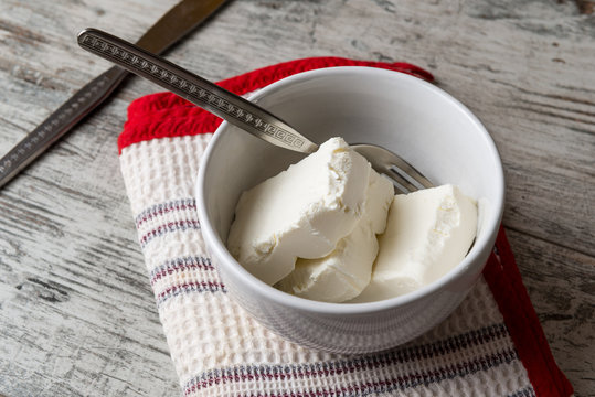 Pezzi di formaggio cremoso in una tazza di ceramica bianca su un tavolo di legno