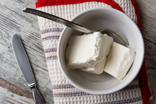 Pezzi di formaggio cremoso in una tazza di ceramica bianca su un tavolo di legno