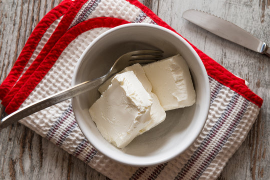 Pezzi di formaggio cremoso in una tazza di ceramica bianca su un tavolo di legno