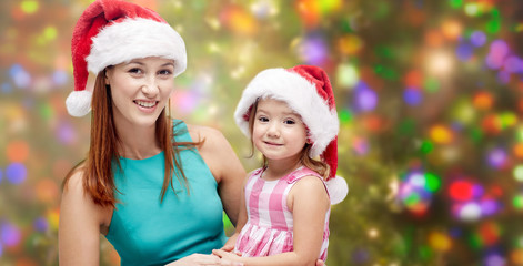 happy mother and little girl in santa hats